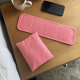 HydroHeat back wrap laid flat on a nightstand with a pouch and mug