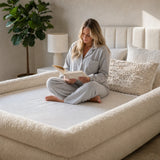 Woman reading cross-legged inside The Cocoon bordered nest fitted sheet